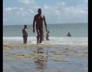 Bare dude with truly monster immense pipe ambling beach